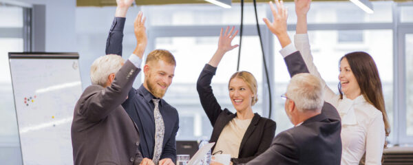 An image showing a group of business professionals in a modern office environment, celebrating a success.